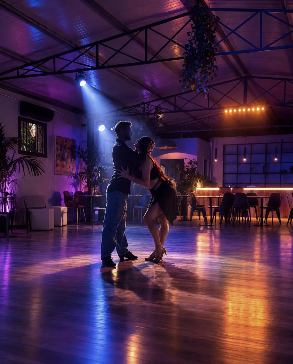 Due ballerini in sala sotto luci viola e blu
